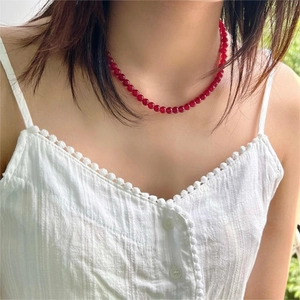 Detailed view of red agate beaded necklace worn with a white bohemian style top