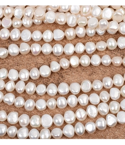 Macro shot of 9-10mm baroque freshwater pearls with natural luster on brown sandy texture