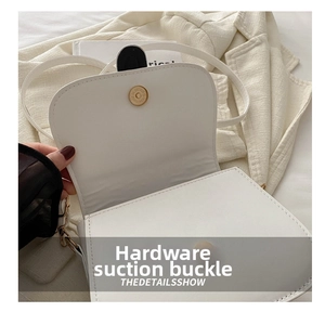 Detail showing the white bag's fine texture and gold round magnetic hardware clasp