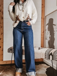 Detail van high waist jeans met wijde pijpen en wit vest met paardenprint dessin