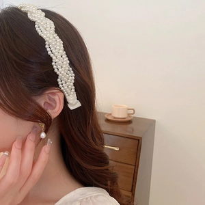 Close-up of model wearing multi-layered white pearl headband with elegant fabric pleats