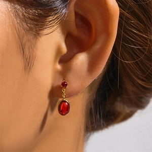Close-up of 925 silver gold-plated earrings with red gemstones on a model ear