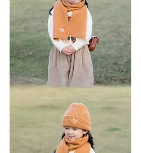 Detail of ginger yellow knitted beanie and scarf set featuring white heart embroidery