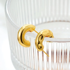 French style gold-plated C-shape textured hoop earrings on a clear glass edge