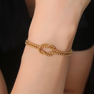 Double-layered gold stainless steel beaded cross bracelet with knot detail on wrist