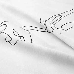 Close-up of minimalist line art print on soft white fabric with touching hands design