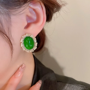 Close-up of vintage emerald green heart earring with clear zircon crystals on model