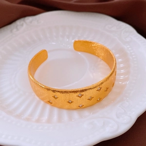 Detail of 18k gold plated cuff bracelet with star patterns and sparkling zircon stones