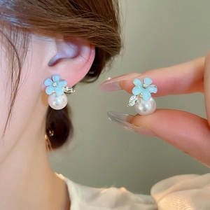 Detailed view of light blue flower pearl earrings with sparkling zircon leaf accents