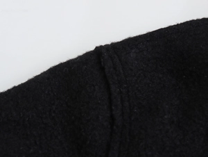 Détail de la veste noire en laine montrant la texture du tissu et les coutures doubles