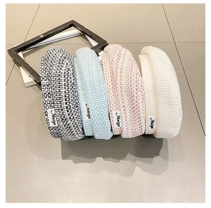 Detail view of tweed berets in plaid, blue, pink, and beige with stylish side labels