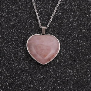 Fashionable pink heart-shaped crystal pendant necklace with silver twisted chain on black background