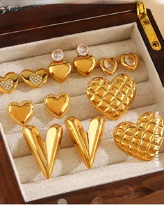 Macro view of 18K gold plated stainless steel heart earrings and rings in a wooden jewelry box