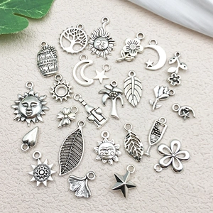 Flat lay of vintage silver DIY charms featuring sun, moon, and floral alloy pendants