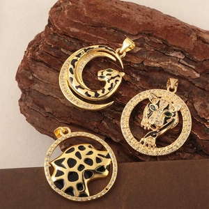 Three gold cheetah pendants with black enamel and rhinestones on natural bark