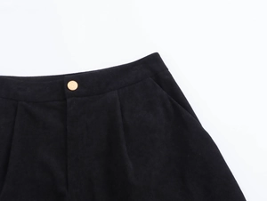 Dettaglio dei pantaloncini in velluto a coste nero con bottone dorato e trama