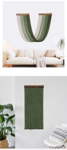Dettaglio dell'arazzo bohémien con nappe verde scuro e asta di supporto in legno massello