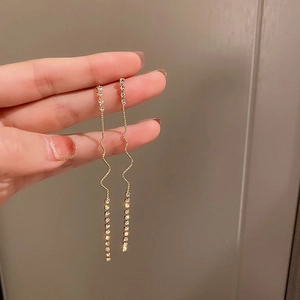 Gros plan des boucles d'oreilles feuilles émeraude et diamant aux vagues dorées élégantes