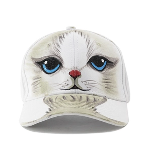 Close-up of hand-painted blue-eyed cat face print on a white cotton baseball cap