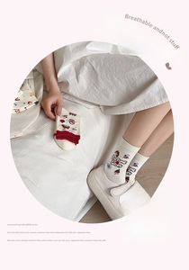 Détail de chaussettes mi-mollet en coton blanc avec rayures rouges et broderie ours