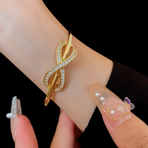 Detail of infinity gold-plated bangle with pave-set zircons on black background