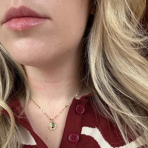 Golden stainless steel necklace featuring a round pendant with green and red zircon stones