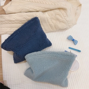 Detail showing plush teddy fleece makeup bags in deep blue and light blue with soft textures