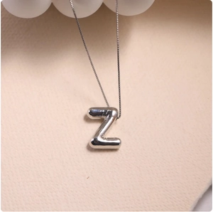 Macro shot of silver 3D balloon-style letter Z pendant on a delicate box chain