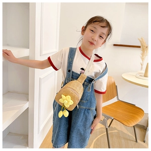 Handwoven straw chest bag for kids featuring a yellow flower on a young girl model