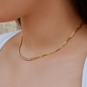 Close-up of gold olive branch necklace with zircon details on a female model neck