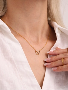 Close-up of a gold butterfly necklace with zircon on a model wearing a white shirt