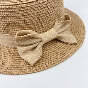 Close-up of fine straw weave texture and striped ribbon bow on sun hat