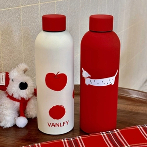 Close-up of white apple and red dachshund patterns on stainless steel thermal bottles