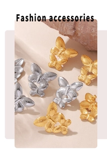 Detail of 18k gold and silver butterfly earrings arranged on a natural stone base