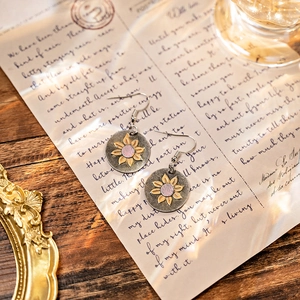 Detail of bohemian sunflower earrings in vintage silver on a retro handwritten letter