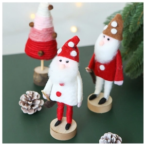 Detail of wool felt Santa dwarf figurines on round wooden stands with festive greenery