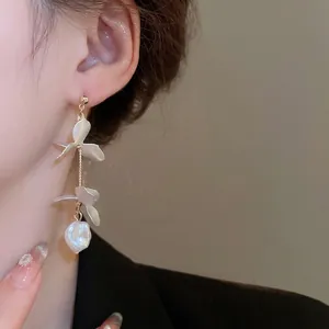 Elegant gold flower petal tassel earrings with white pearls on a female model