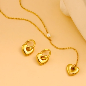 Detail of gold heart jewelry set featuring heart earrings and a pearl heart necklace