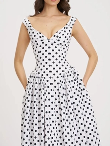 Detail van de diepe V-hals en elegante polkadots op de witte maxi-jurk voor dames