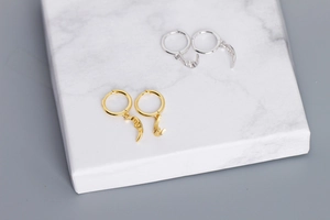 Detail of S925 sterling silver hoop earrings with moon and star charms in gold and silver