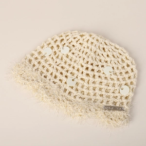Détail d'un bonnet au crochet avec paillettes, bordure en plumes et plaque en métal