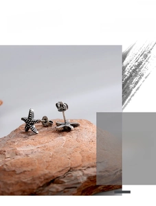 Macro shot of vintage silver starfish stud earrings displayed on a textured mineral stone