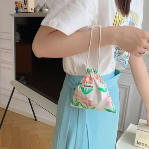 Close-up of a floral drawstring pouch with pink flowers on a cream fabric surface