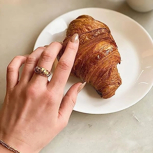 Close-up of golden croissant ring with twisted rope texture worn on index finger