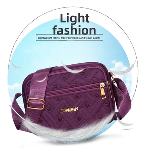 Detail of purple crossbody bag with heart-quilted pattern and gold hardware accents
