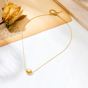 Close-up of golden heart pendant necklace on vintage paper with a dried rose background