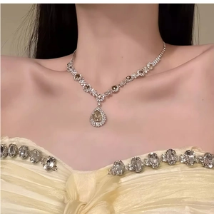 Elegant silver necklace with green and clear pear-cut gems worn by a model