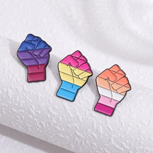 Pines esmaltados creativos en forma de puño con banderas LGBTQ sobre fondo blanco texturizado