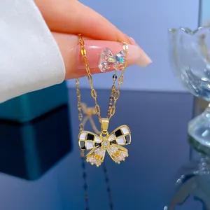 Détail d'un pendentif papillon en titane doré avec motif à damier et zircons brillants
