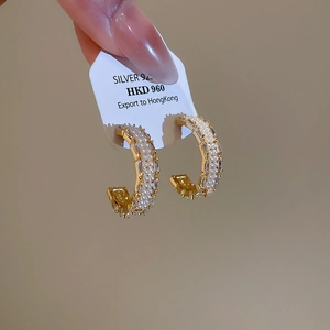 Detail shot of C-shaped earrings with gold plating, white pearls and zircon accents